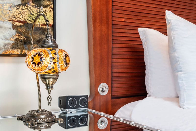 a close-up of a bed with a white pillow and a lamp on a table