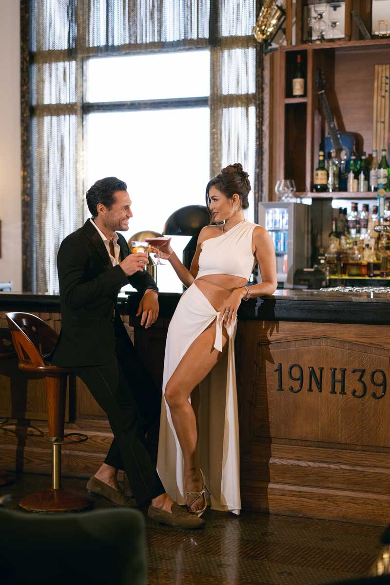 A man and woman in a bar with a black countertop and wooden base.