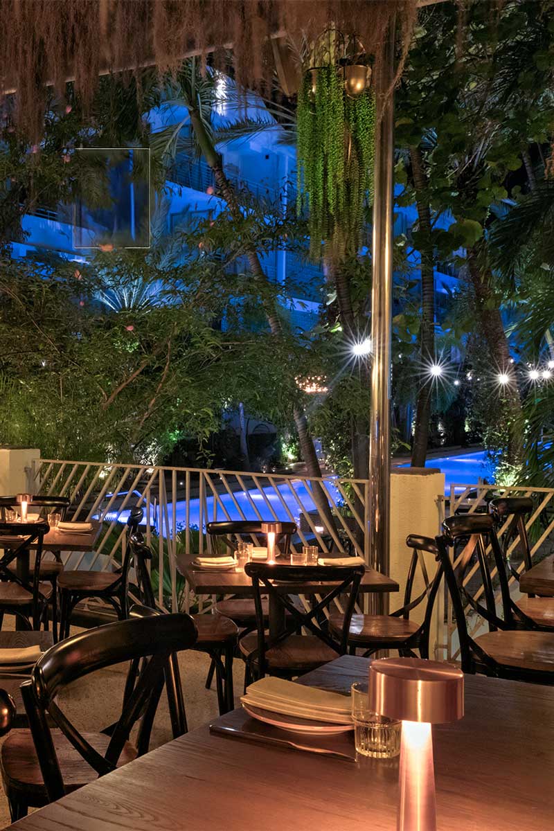 a dimly lit outdoor dining area with tables and chairs